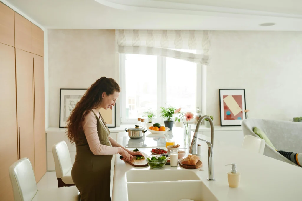 Mujer embarazada preparando una comida saludable en casa durante el segundo trimestre del embarazo